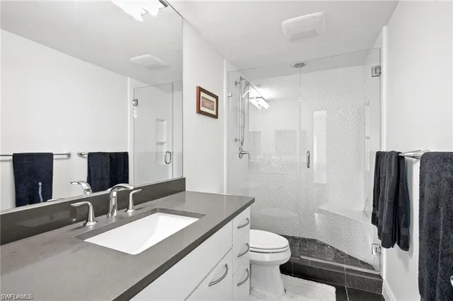 a bathroom with a granite countertop sink toilet a large mirror and shower