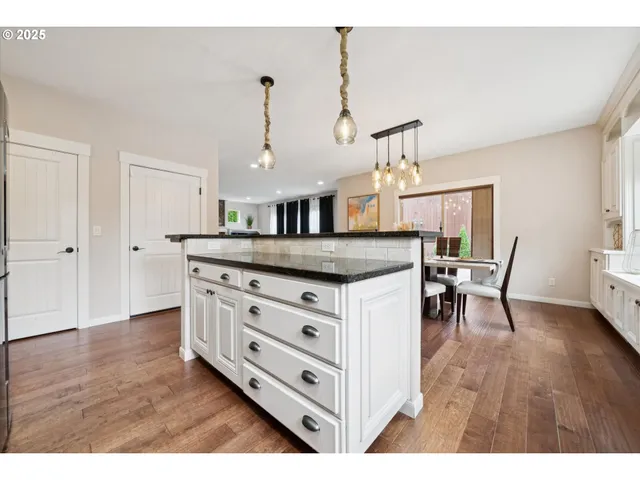 a kitchen with stainless steel appliances kitchen island granite countertop a wooden floor