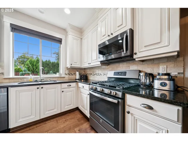 a kitchen with stainless steel appliances granite countertop white cabinets granite counter tops and a window