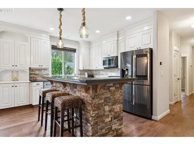 a kitchen with stainless steel appliances granite countertop a refrigerator a stove a sink and a microwave