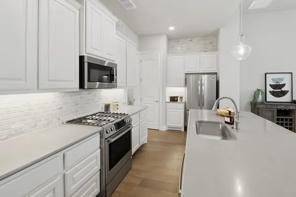 a kitchen with stainless steel appliances a stove a sink a microwave and refrigerator