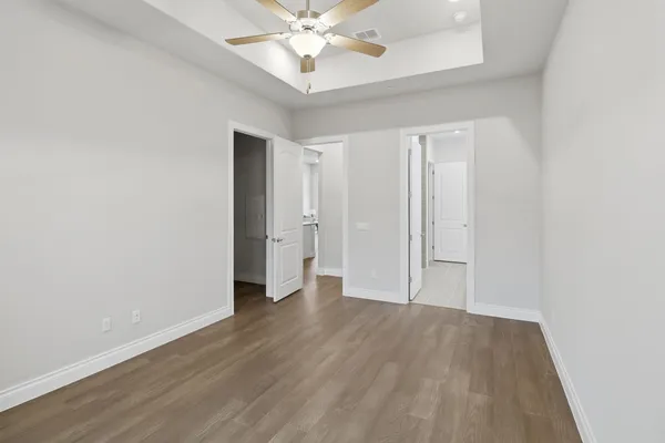 an empty room with wooden floor and fan