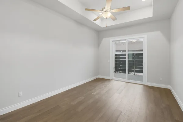 an empty room with wooden floor fan and windows