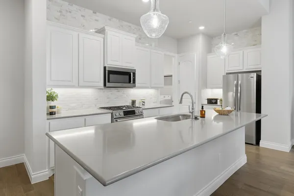 a kitchen with stainless steel appliances a sink a stove a refrigerator a center island and cabinets