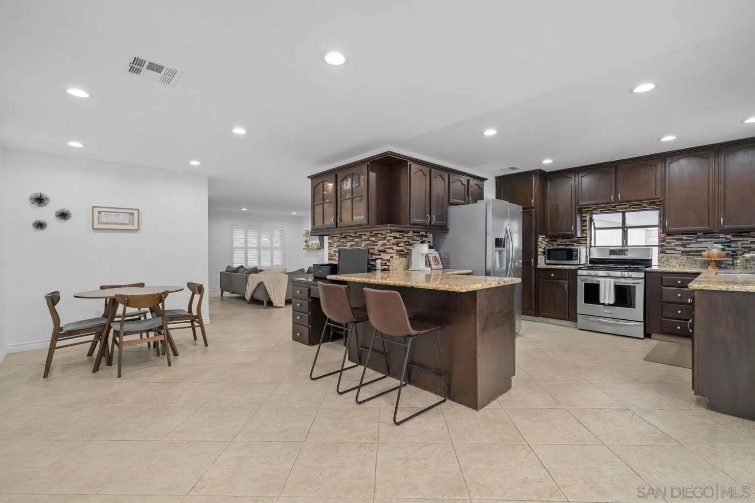 9026 Hamilton Street Rancho Cucamonga, CA 91701 - Photo 11 of 26 a kitchen with kitchen island granite countertop wooden cabinets and center island with chairs