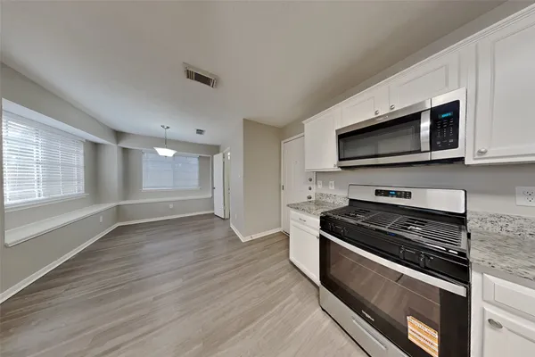a kitchen with granite countertop wooden cabinets and a stove top oven