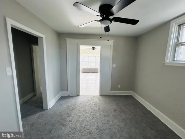 an empty room with a ceiling fan and a window