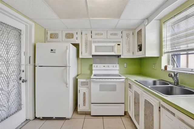 a kitchen with cabinets appliances a sink and a window