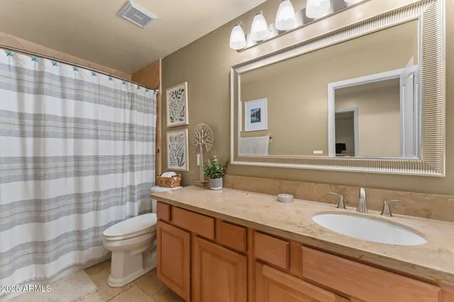 a bathroom with a granite countertop sink toilet a mirror and shower curtain