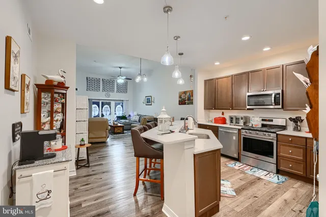 a kitchen with stainless steel appliances kitchen island granite countertop a sink dishwasher stove top oven and cabinets with wooden floor