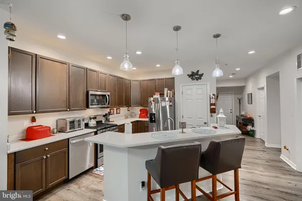 a kitchen with stainless steel appliances kitchen island granite countertop a sink cabinets and wooden floor