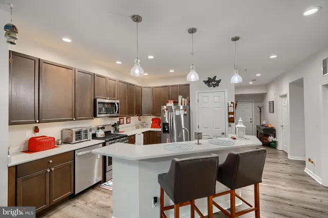 a kitchen with stainless steel appliances kitchen island granite countertop a sink cabinets and wooden floor