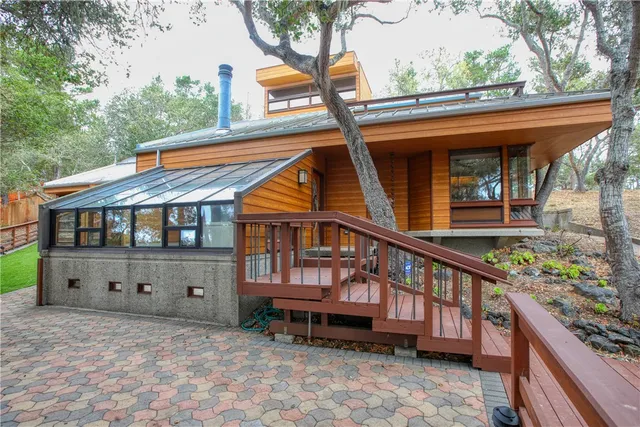 a view of a house with a wooden deck and a garden