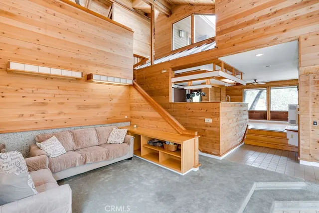 a living room with furniture a flat screen tv and a floor to ceiling window