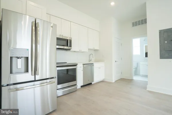 a kitchen with stainless steel appliances white cabinets and a refrigerator