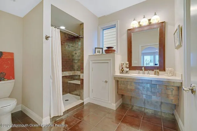 a bathroom with a granite countertop sink a toilet and shower