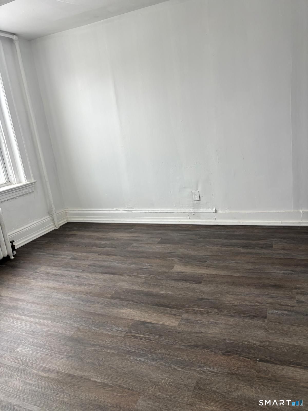 86 Pequonnock Street, Unit 20 Bridgeport, CT 06604 - Photo 5 of 5 a view of an empty room with wooden floor and a window