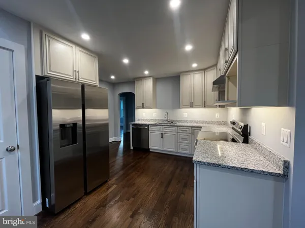 a large kitchen with stainless steel appliances kitchen island granite countertop a stove a sink dishwasher and a refrigerator with wooden floor