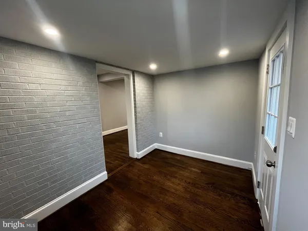 an empty room with wooden floor fireplace and windows