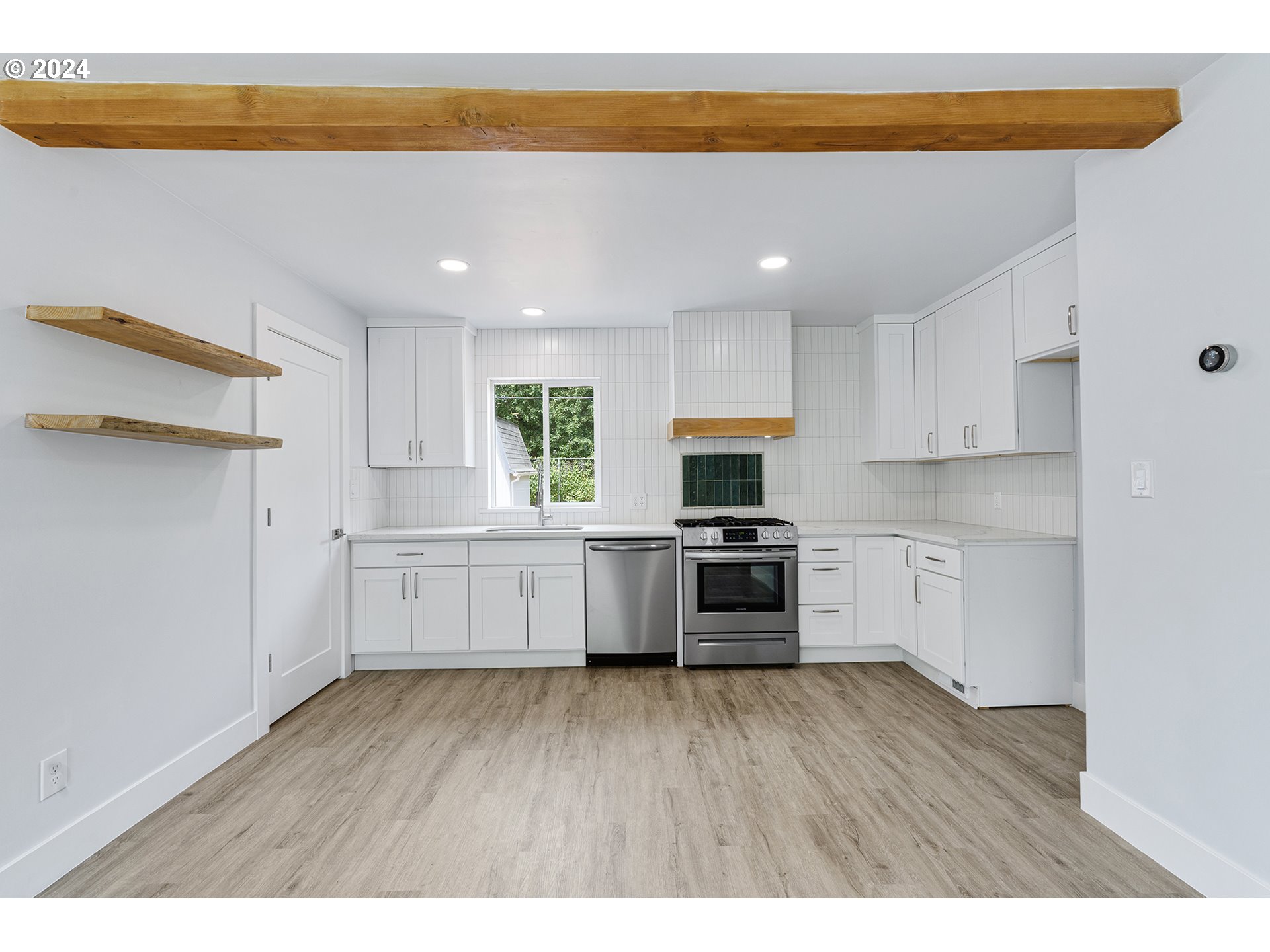 9045 Southeast Morrison Street Portland, OR 97216 - Photo 10 of 35 a kitchen with white cabinets and wooden floor