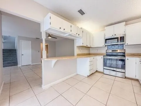a view of an empty room and chandelier fan