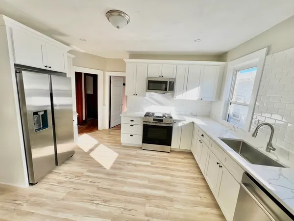 a large kitchen with stainless steel appliances kitchen island granite countertop a refrigerator and a sink