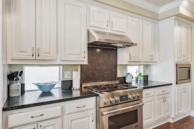 a kitchen with granite countertop white cabinets and stainless steel appliances