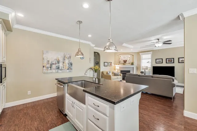 a kitchen with stainless steel appliances granite countertop a sink a stove and a wooden floor