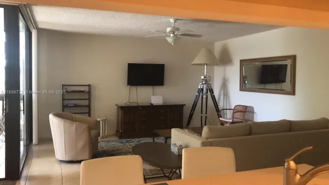 a living room with furniture a flat screen tv and kitchen view