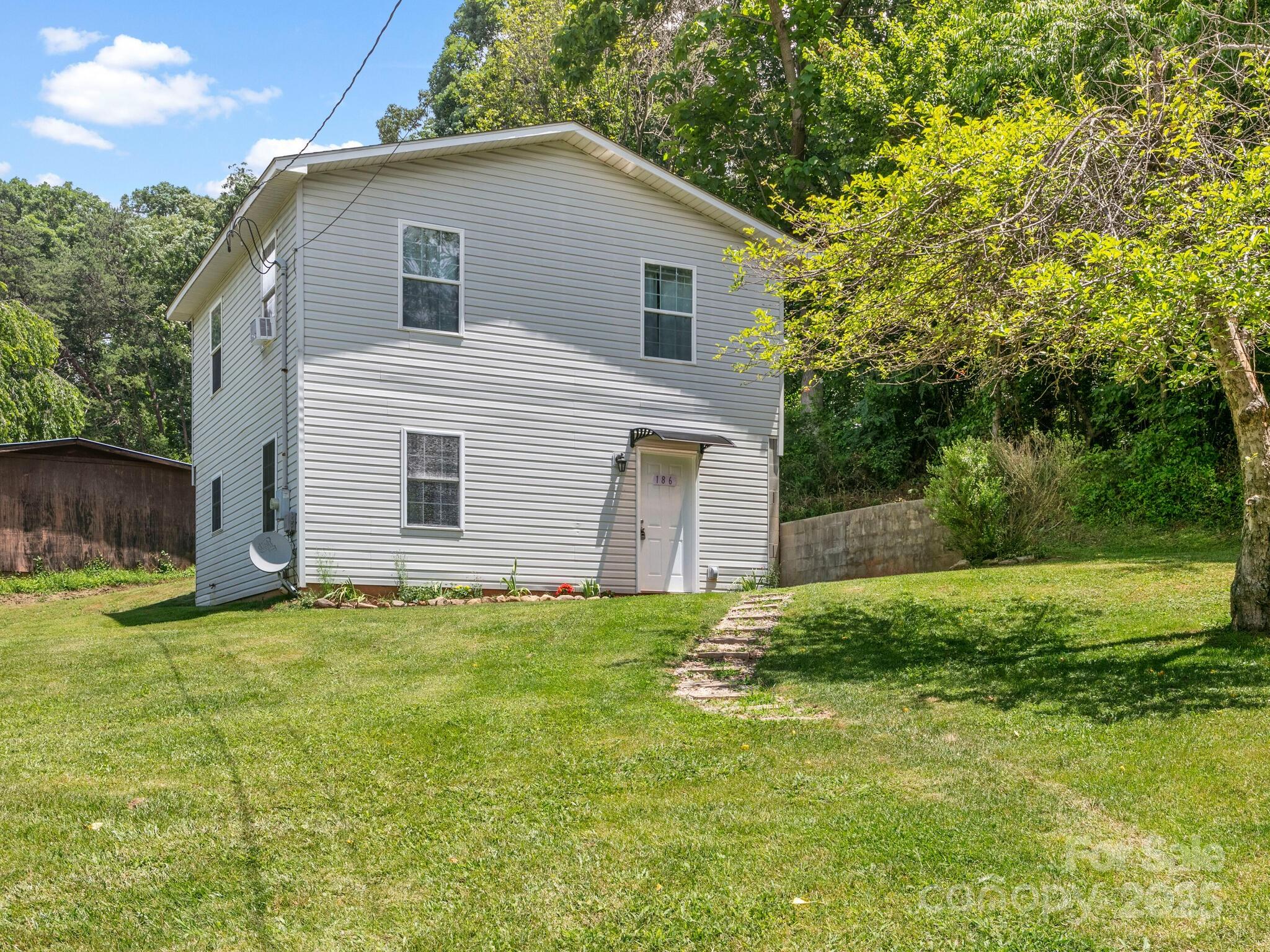 186 Wiggins Road Candler, NC 28715 - Photo 2 of 32 a house that is sitting in the grass with large trees