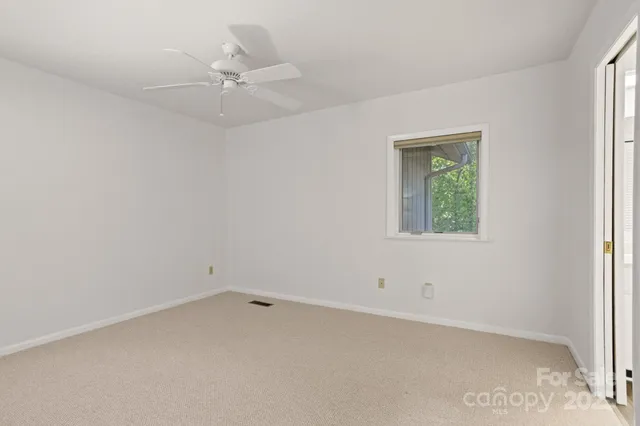 an empty room with a window and a fan