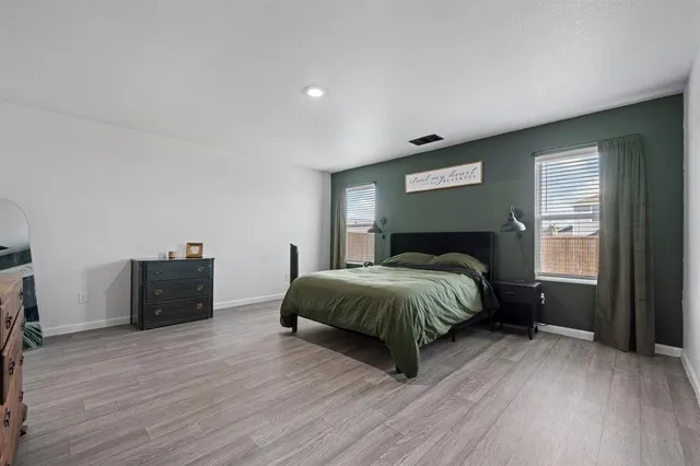 a spacious bedroom with a bed and a dresser with wooden floor