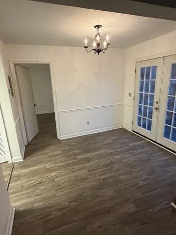 a view of an empty room with wooden floor and chandelier