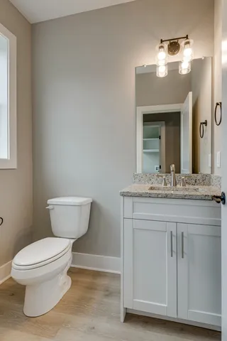 a bathroom with a granite countertop toilet a sink and a mirror