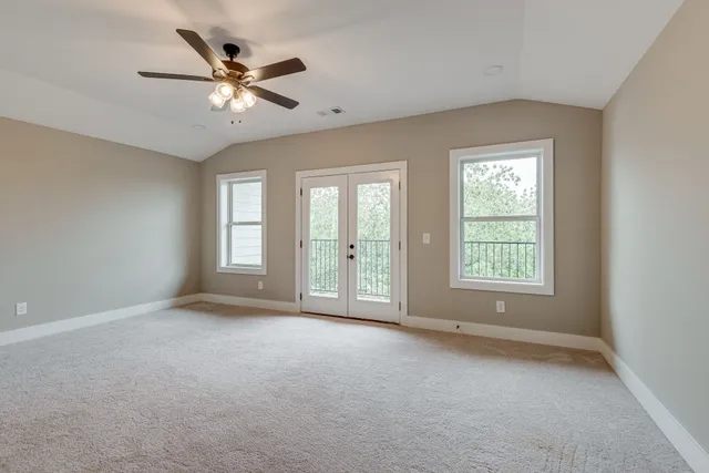 an empty room with chandelier fan and windows