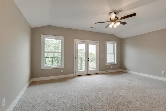 a view of an empty room with chandelier fan and fire place