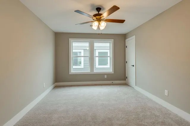 an empty room with a window and a ceiling fan