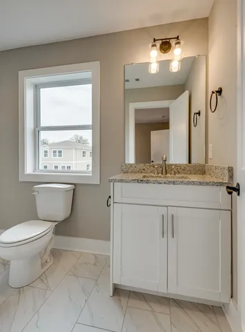 a bathroom with a granite countertop toilet sink and mirror