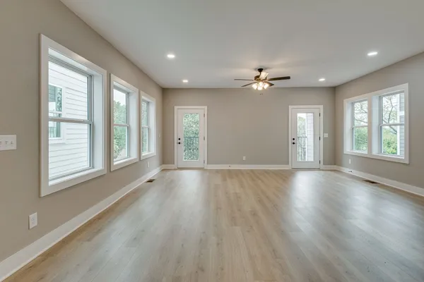a view of an empty room with a window and wooden floor