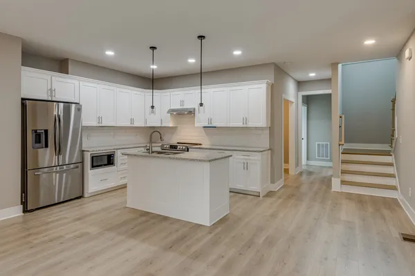 a kitchen with a refrigerator and white cabinets