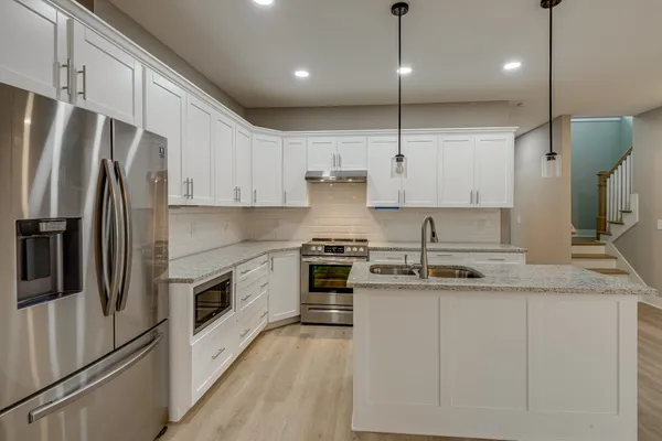 a kitchen with stainless steel appliances granite countertop a sink a stove a refrigerator and island with wooden floor