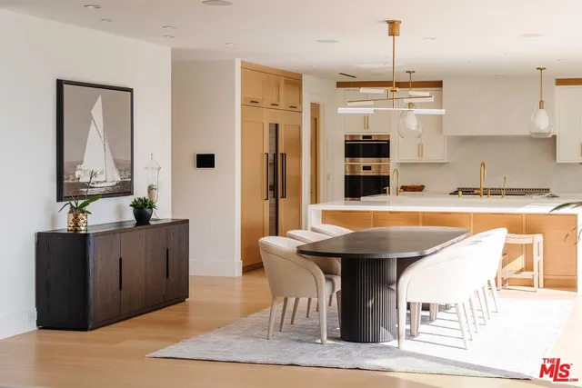 a kitchen with stainless steel appliances kitchen island granite countertop a table chairs in it and wooden floors