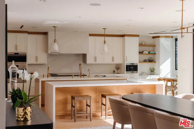 a kitchen with stainless steel appliances granite countertop a table chairs sink and cabinets
