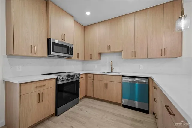 a kitchen with cabinets stainless steel appliances and wooden floor