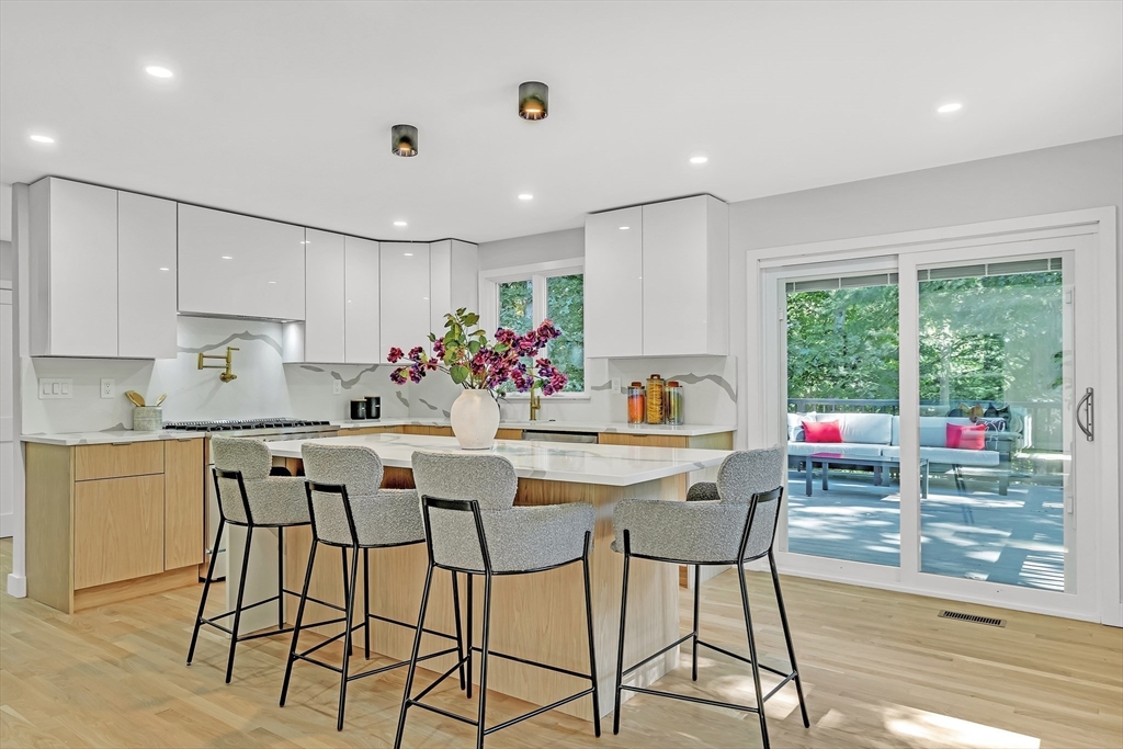 95 Country Club Road Dedham, MA 02026 - Photo 3 of 21 a kitchen with stainless steel appliances kitchen island granite countertop a dining table chairs and white cabinets