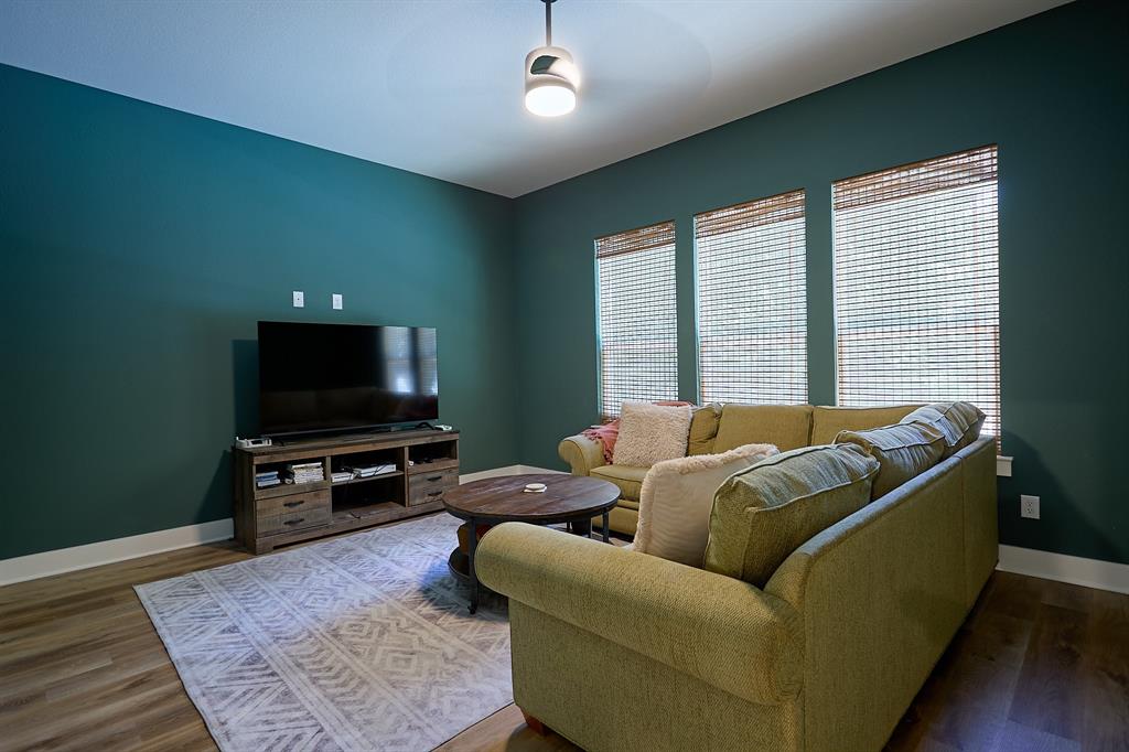 358 Glade Valley Road Azle, TX 76020 - Photo 18 of 35 Living area with deep teal accent walls, wood-finish flooring, and multiple vertical windows featuring woven shades
