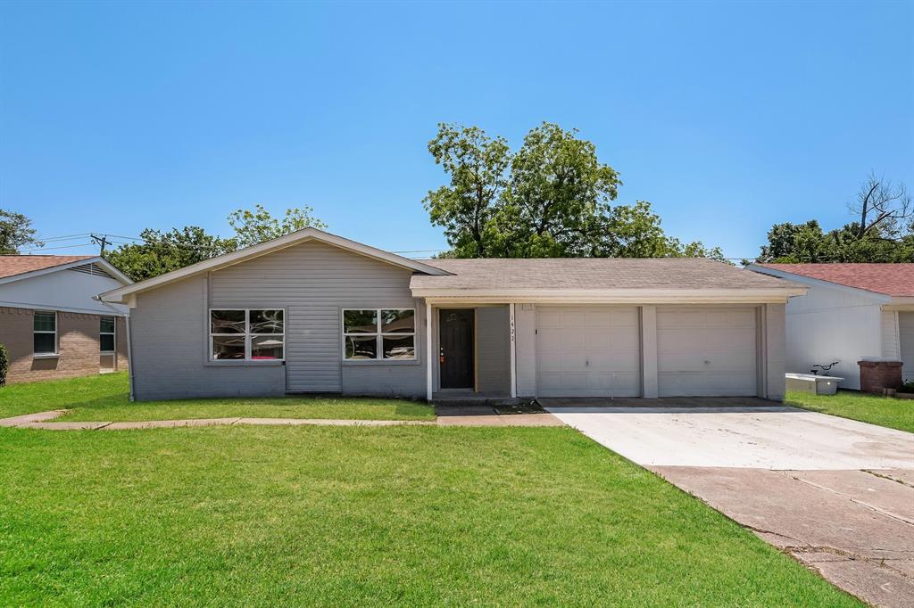 a front view of house with yard and trees in the background