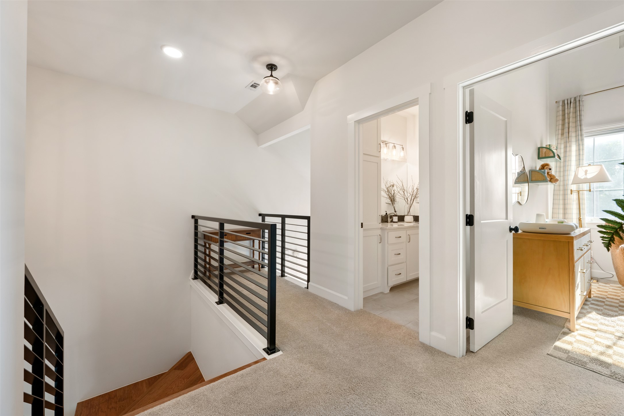 1301 West Street Georgetown, TX 78626 - Photo 35 of 40 A hallway with sleek metal railings leads to a bright bathroom and an adjoining bedroom.