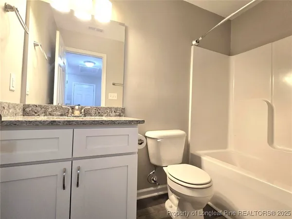 a bathroom with a granite countertop toilet sink and mirror