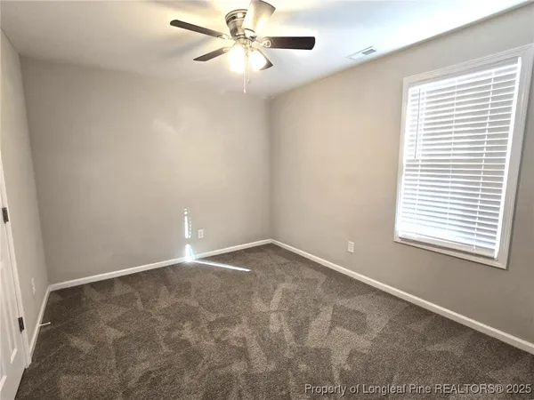 a view of an empty room and chandelier fan